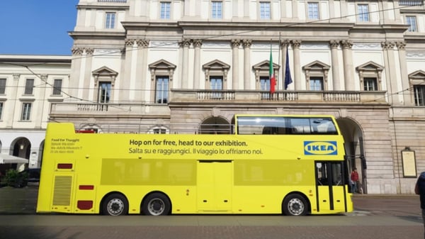 Autobus giallo a due piani brandizzato IKEA parcheggiato davanti alla facciata del Teatro alla Scala di Milano.
