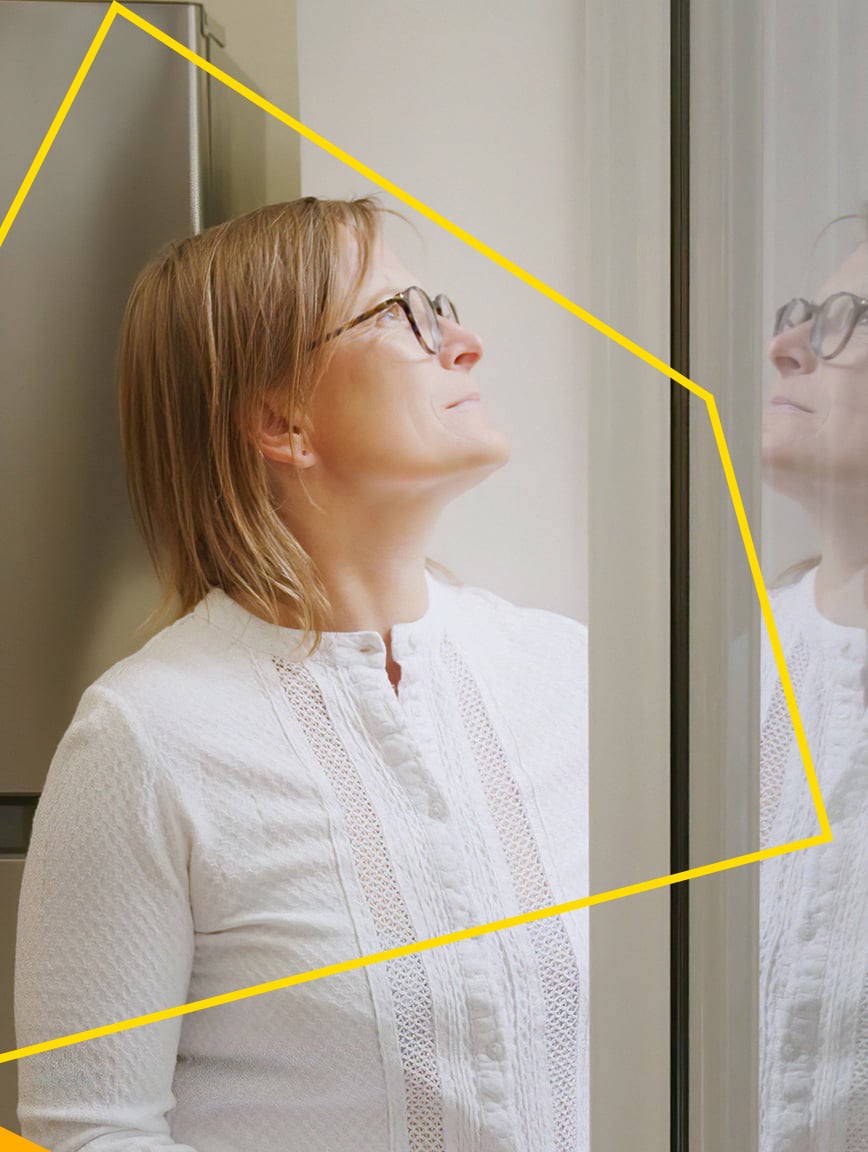 Woman looking out of the window of her home.