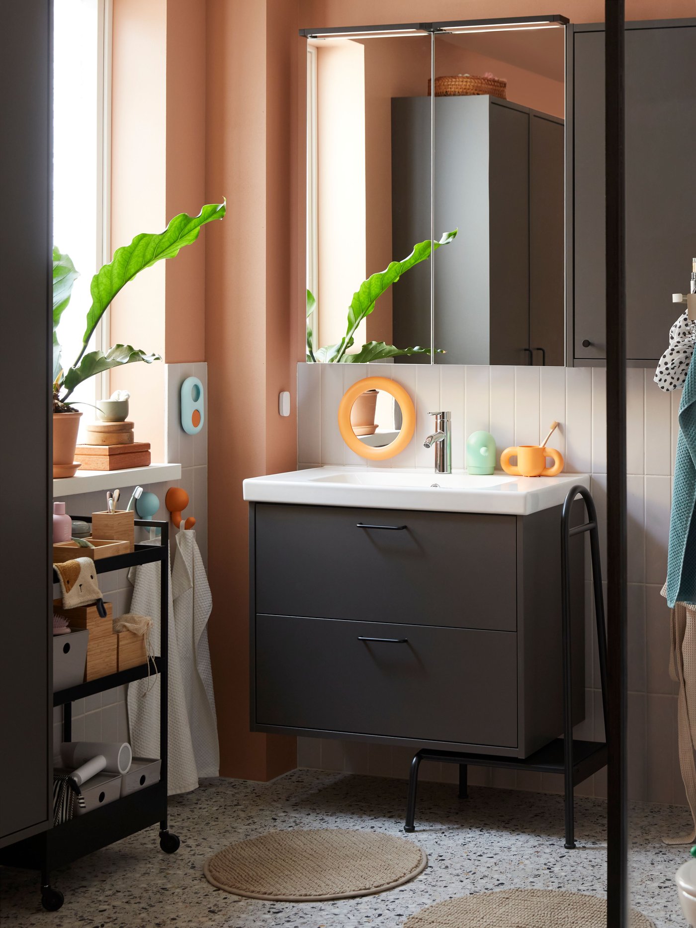 An orange/turquoise HUMLESJÖN hook with suction cup in the bathroom