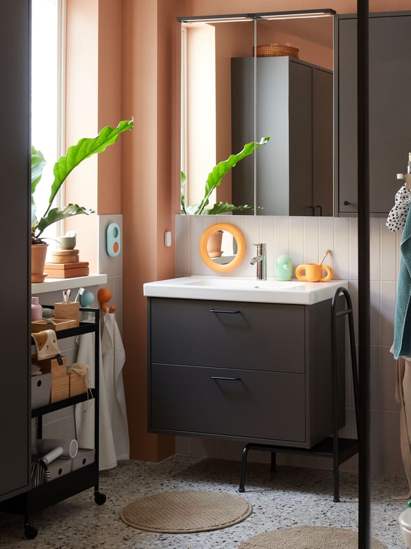 An orange/turquoise HUMLESJÖN hook with suction cup in the bathroom