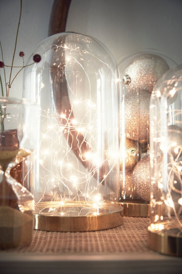Arrangiere ein dezentes Lichterspiel unter einer Glasglocke.
