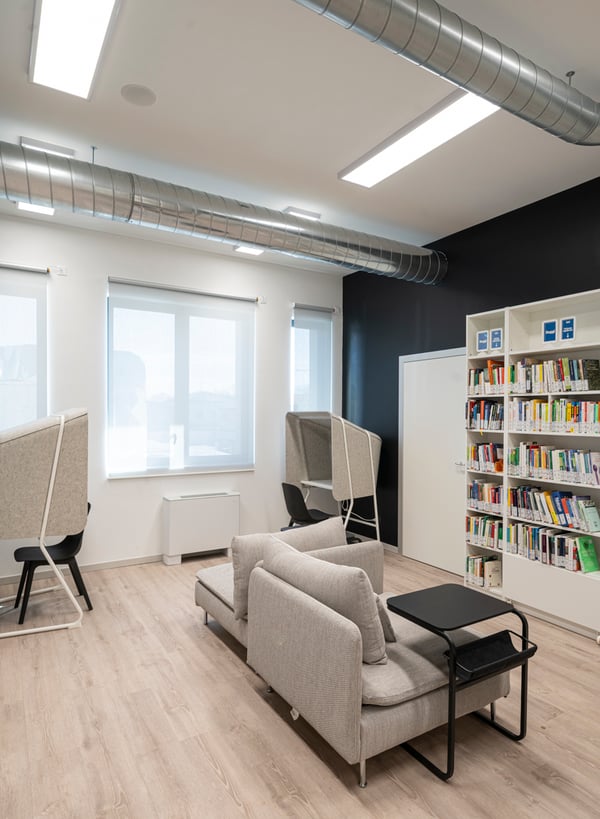 Una zona della biblioteca attrezzata con divani SÖDERHAMN, tavolini OLSERÖD e isola ufficio MITTZON.