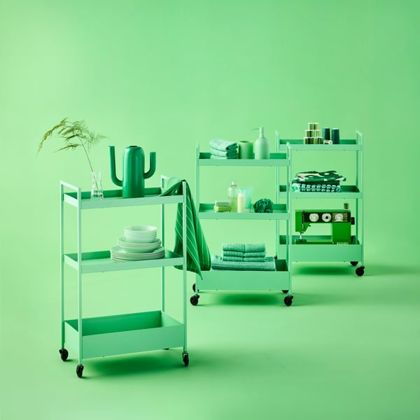 Three light green NISSAFORS trolleys on castors loaded with small bathroom, dinnerware and sewing items.