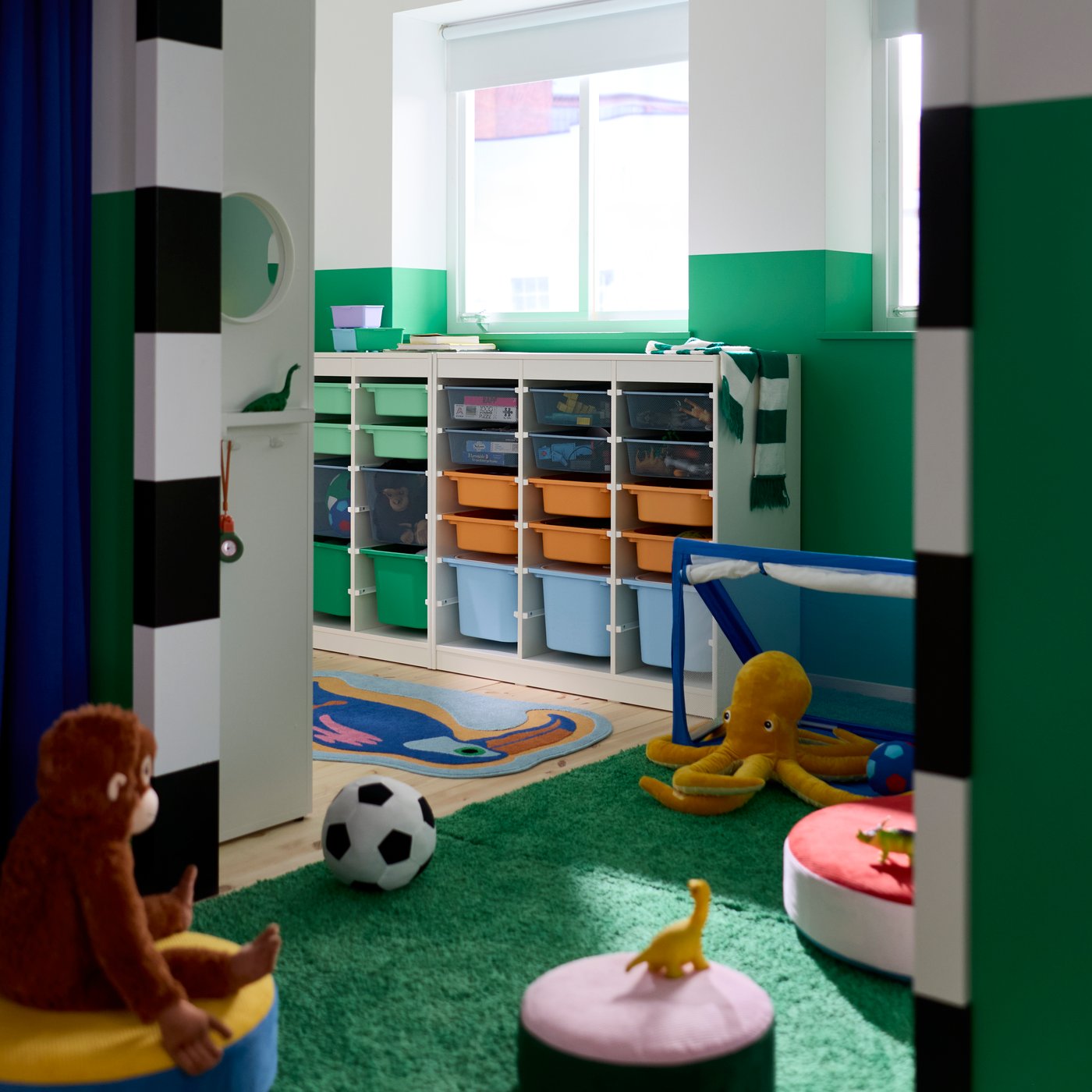 A children’s bedroom with walls painted green and white and a TROFAST system with boxes in different sizes and colours.