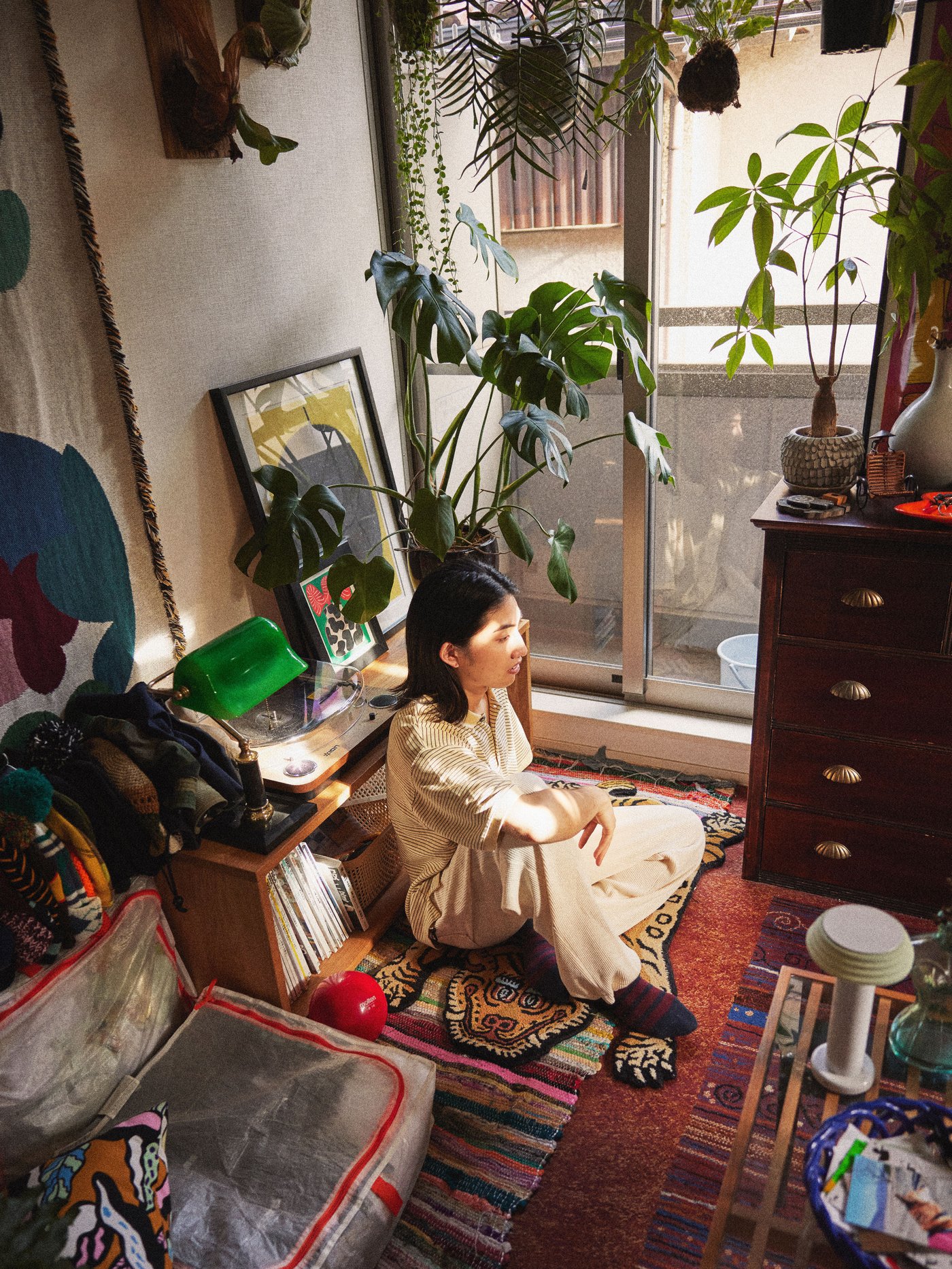 Eine Person sitzt in ihrem Wohnzimmer auf dem Fussboden. Um sie herum befinden sich viele Möbel.