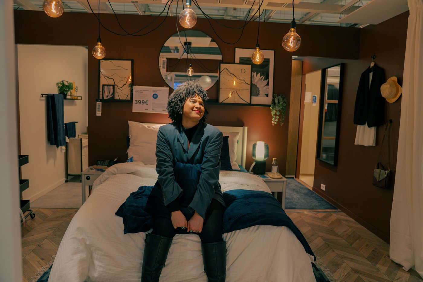 Shadia sitting on a bed in the IKEA stores showroom.