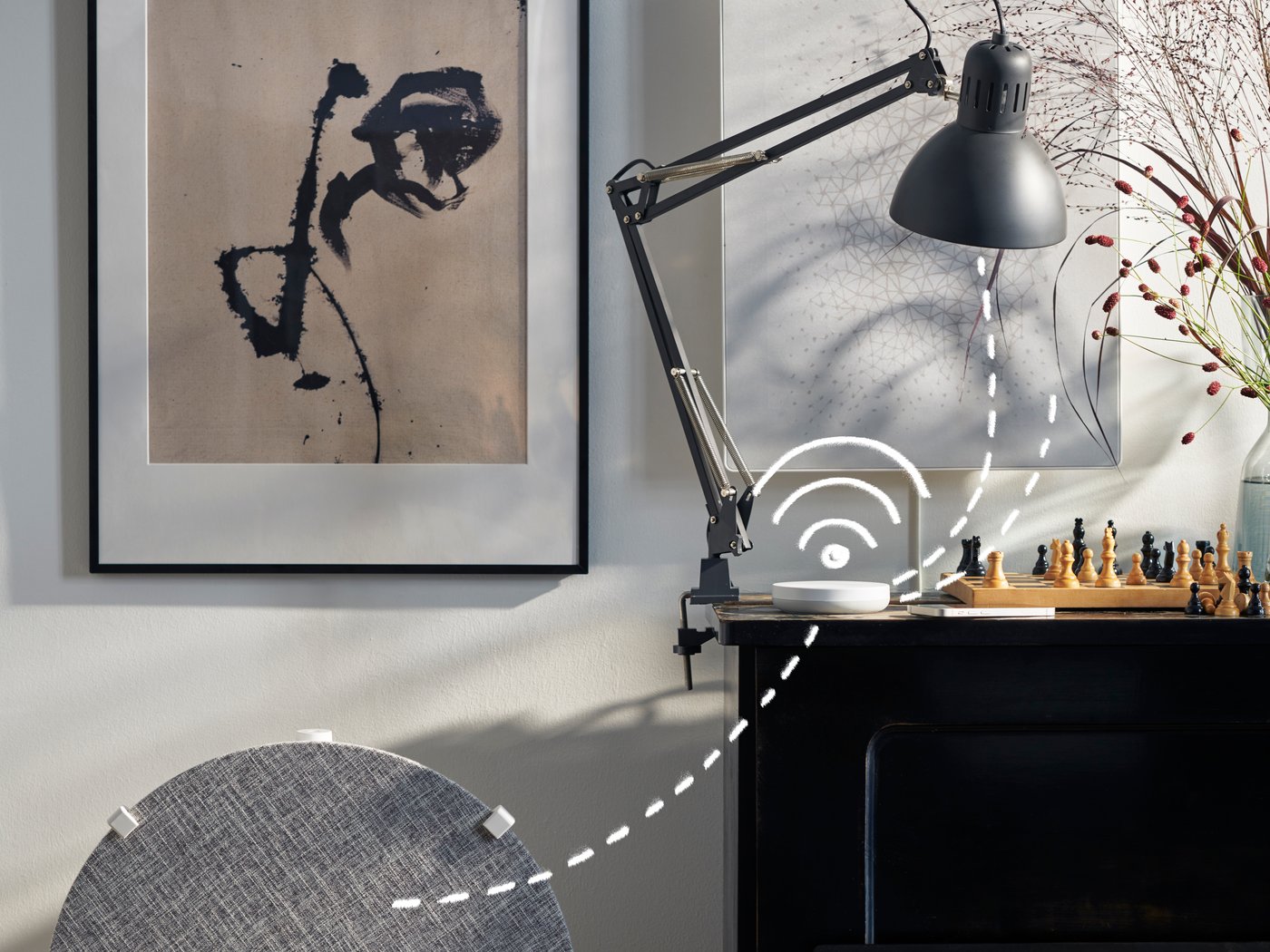 A modern desk setup featuring a black lamp, a white Wi-Fi router, and decorative items against an art-adorned wall.