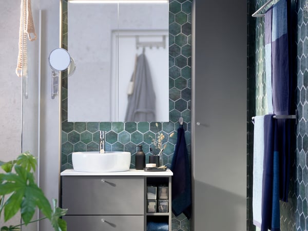Bathroom space with multiple cabinets and a large mirror above the sink 