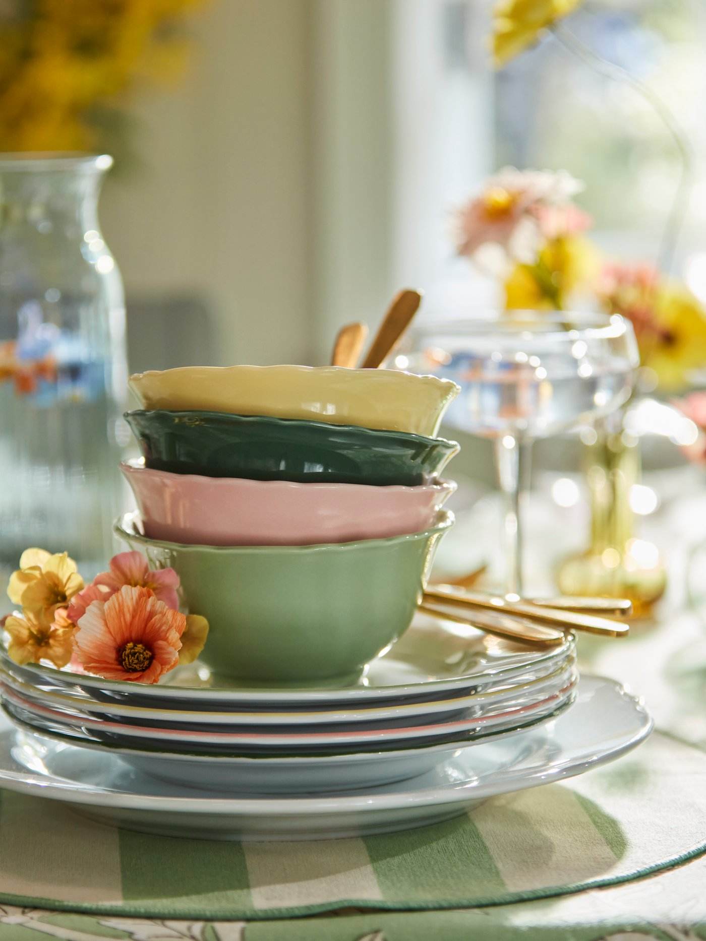 En stabel med UPPLAGA boller i gult, grønt og rosa, plassert på UPPLAGA sidetallerkener og en stripete SMÖRFISK spisebrikket.