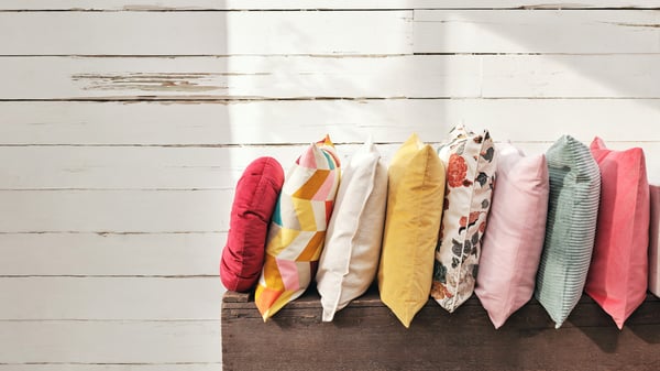 Cushions in different covers, including off-white HERVOR cushion covers and green HALLVI cushion covers, sit on beds.
