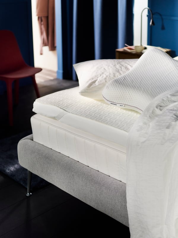 A VÅGSTRANDA hybrid mattress on a TUFJORD bed with a TUSSÖY mattress pad, a ROSENKÄRM pillow and a white comforter on top.