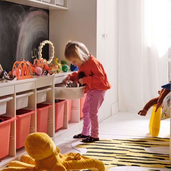A girl is looking for toys in a TROFAST cupboard
