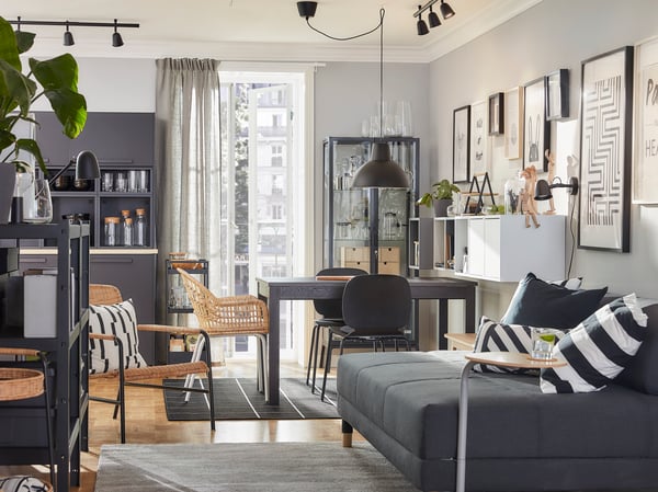 Salón y comedor en uno decorado a juego con muebles de ratán y combinación de colores en marrón, gris y antracita.