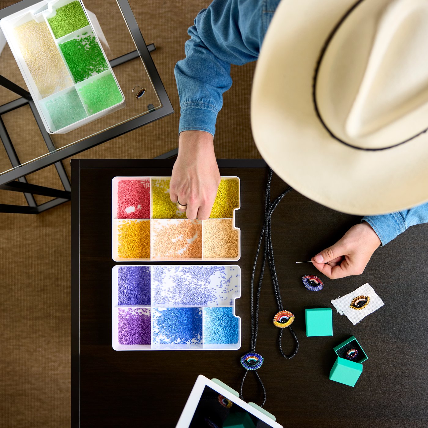 Top view of person crafting with colorful pearls stored in a white KUGGIS insert with five compartments on a table.