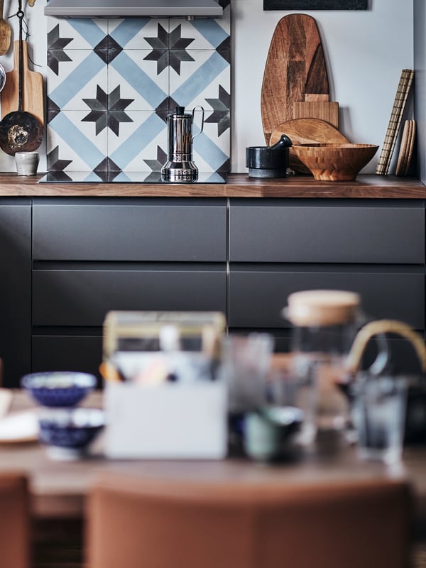 A modern kitchen with VOXTORP fronts in dark gray, with a wooden worktop and a kitchen tile backsplash.