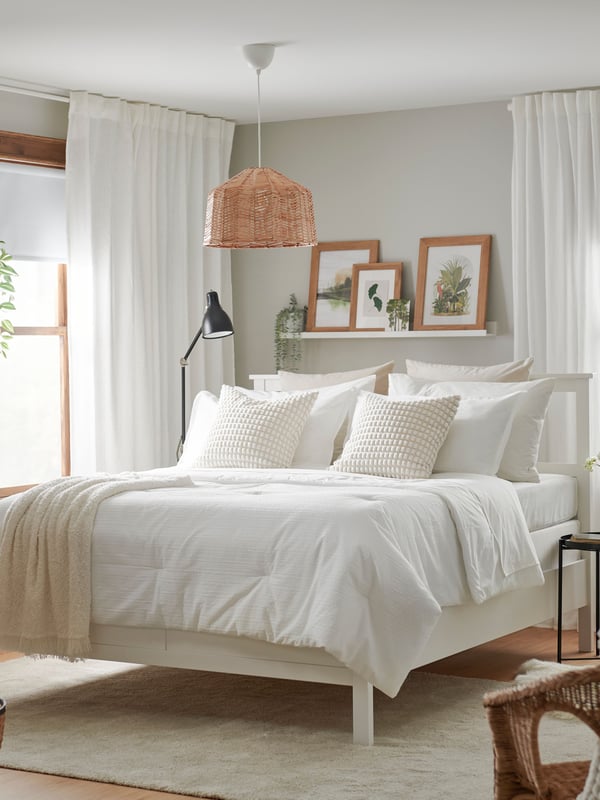 A bed made with a white LUKTVICKER comforter and a beige throw blanket on the side of the bed.