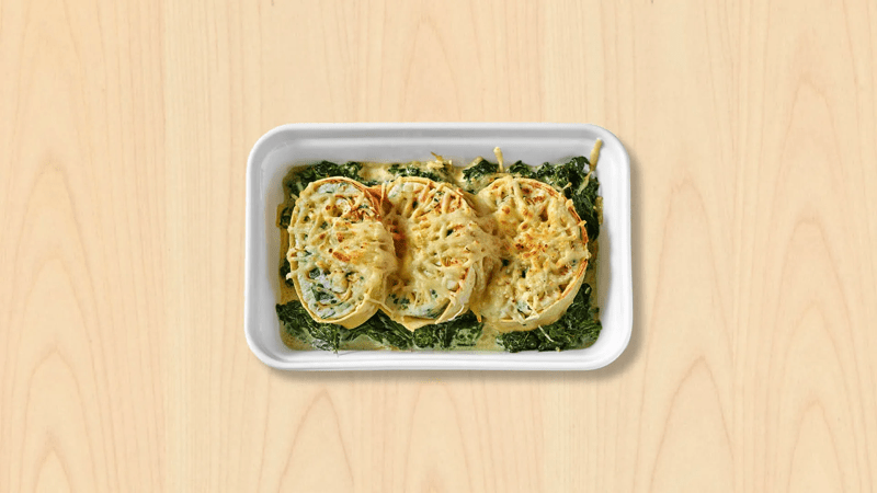 Un plat de riccioles à la ricotta et aux épinards dans une assiette sur fond bois