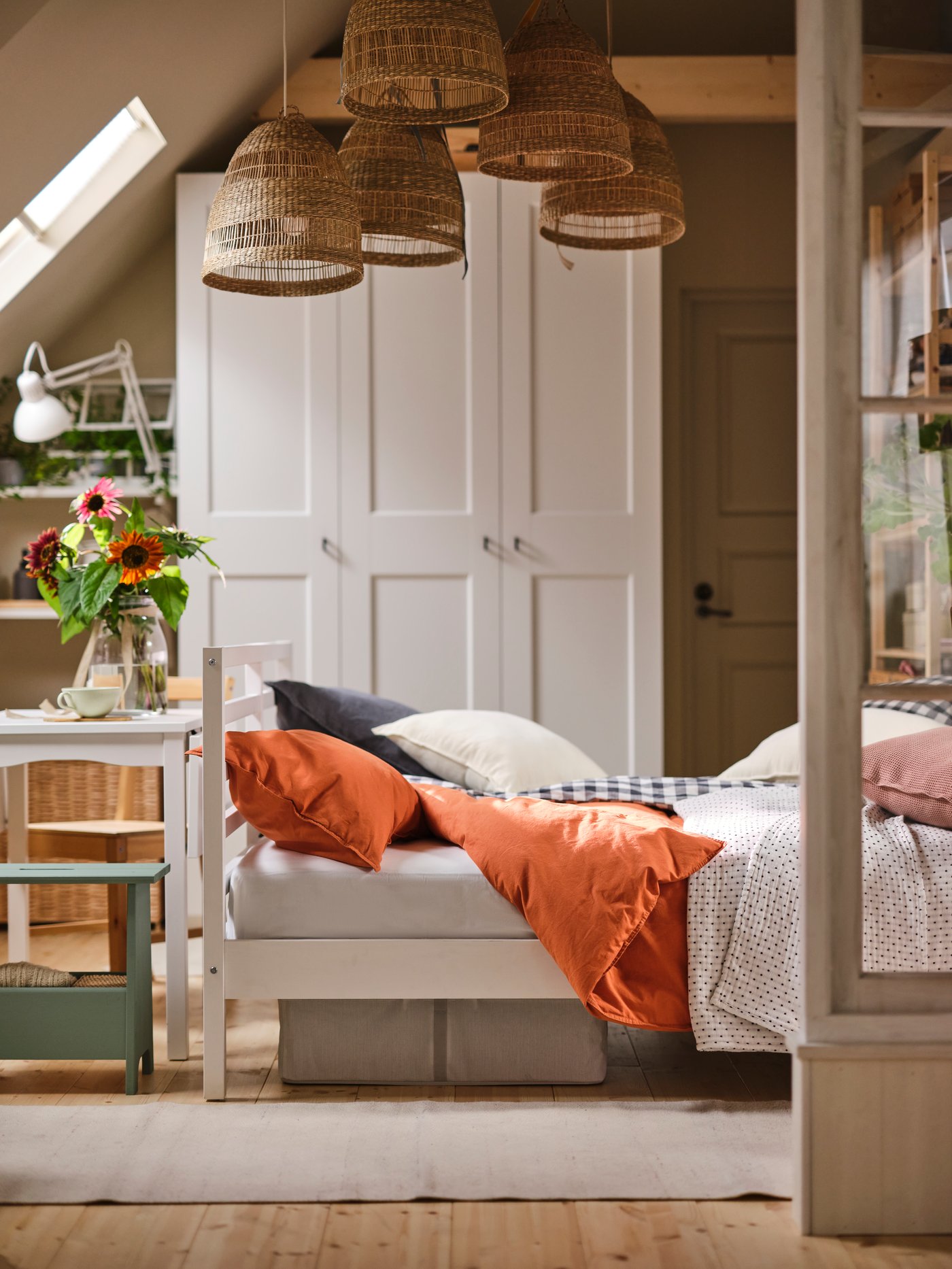 A white TARVA bed in a rustic bedroom with five TORORED pendant lampshades above it, in front of a white PAX/GRIMO wardrobe.