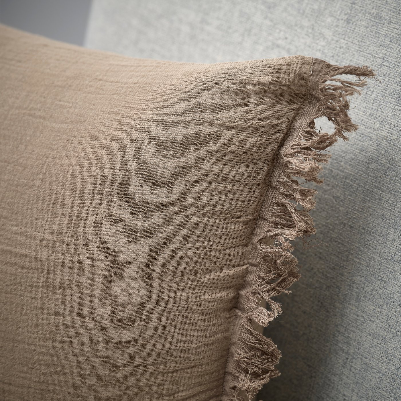 Nahaufnahme eines braun VALLKRASSING Kissens mit Knittereffekt und Fransen.