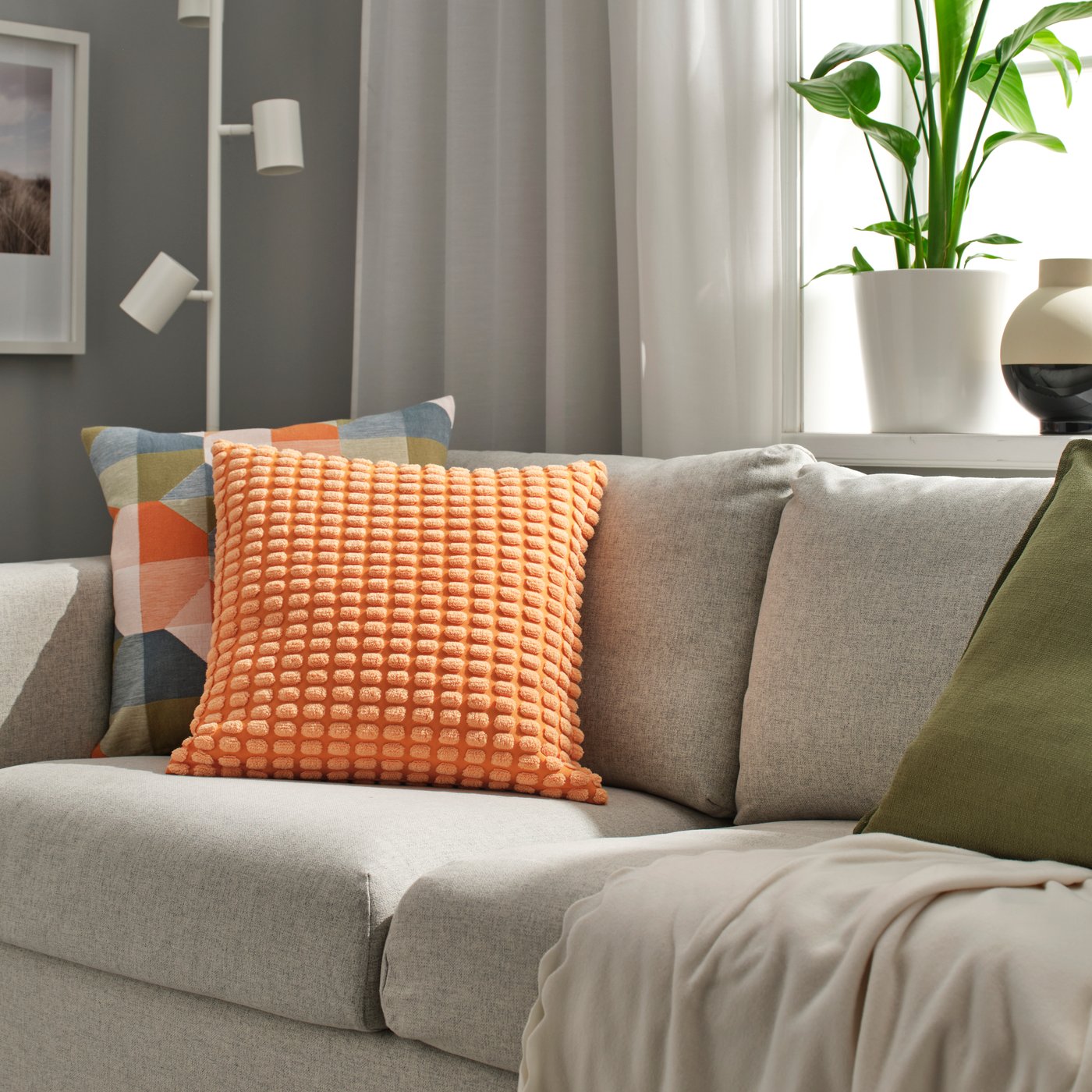 A light orange SVARTPOPPEL cushion cover