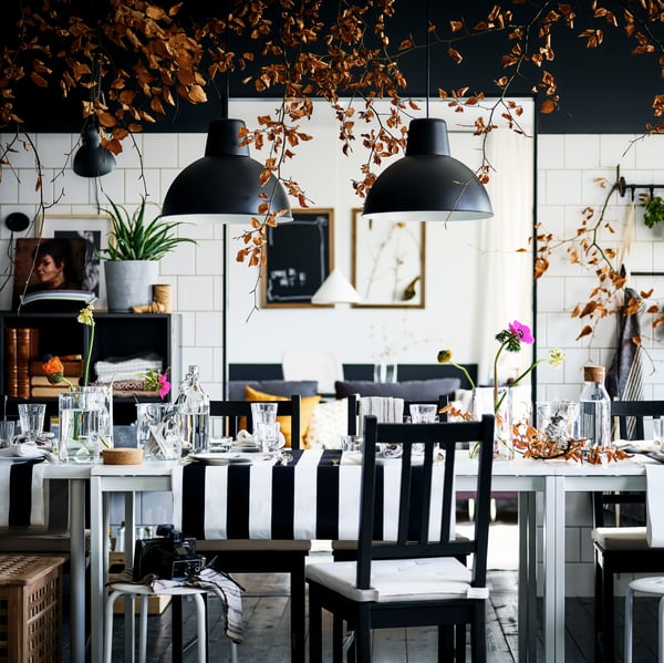 A decked-out black-and-white dining area with brown-black STEFAN chairs and MARIUS stools round two white MELLTORP tables.