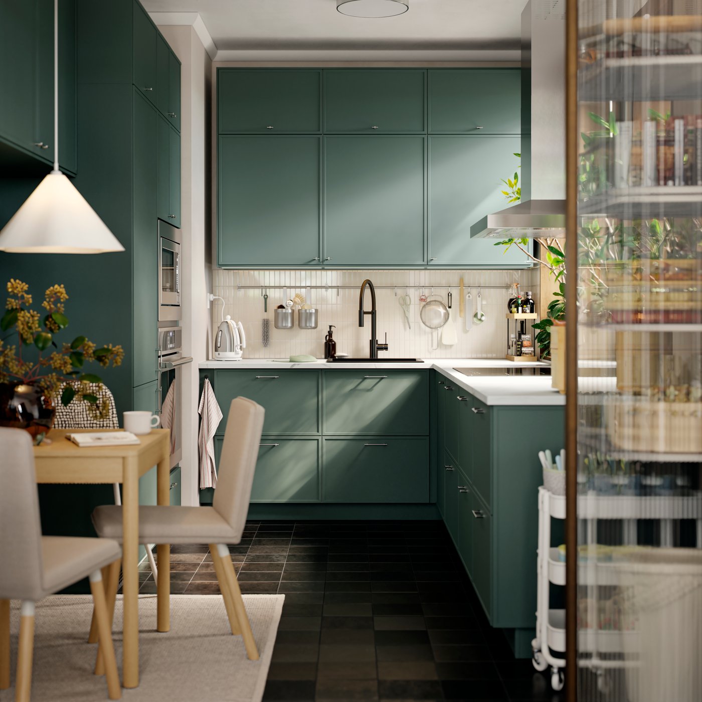 A small kitchen has base, wall and top cabinets, going all the way to the ceiling and there’s a small table with a chair.