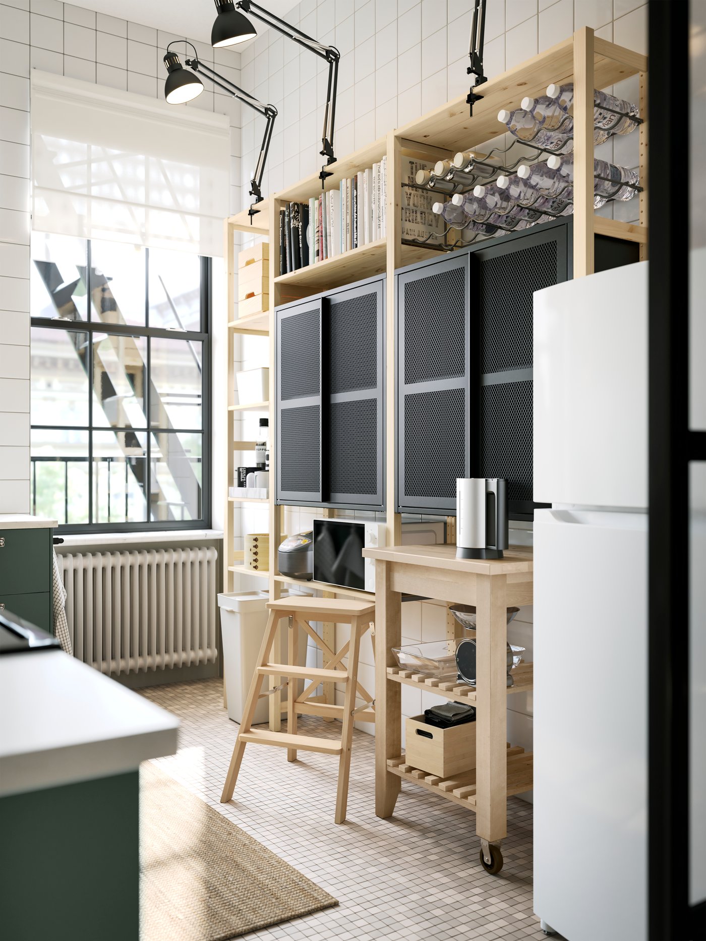 Une étagère IVAR en pin avec deux armoires en filet noir avec portes et des lampes de travail gris foncé sur le dessus, ainsi qu’une desserte.