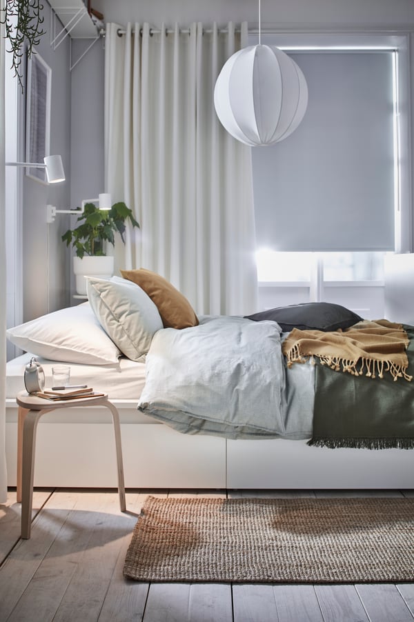 A natural LOHALS rug, flatwoven in the bedroom