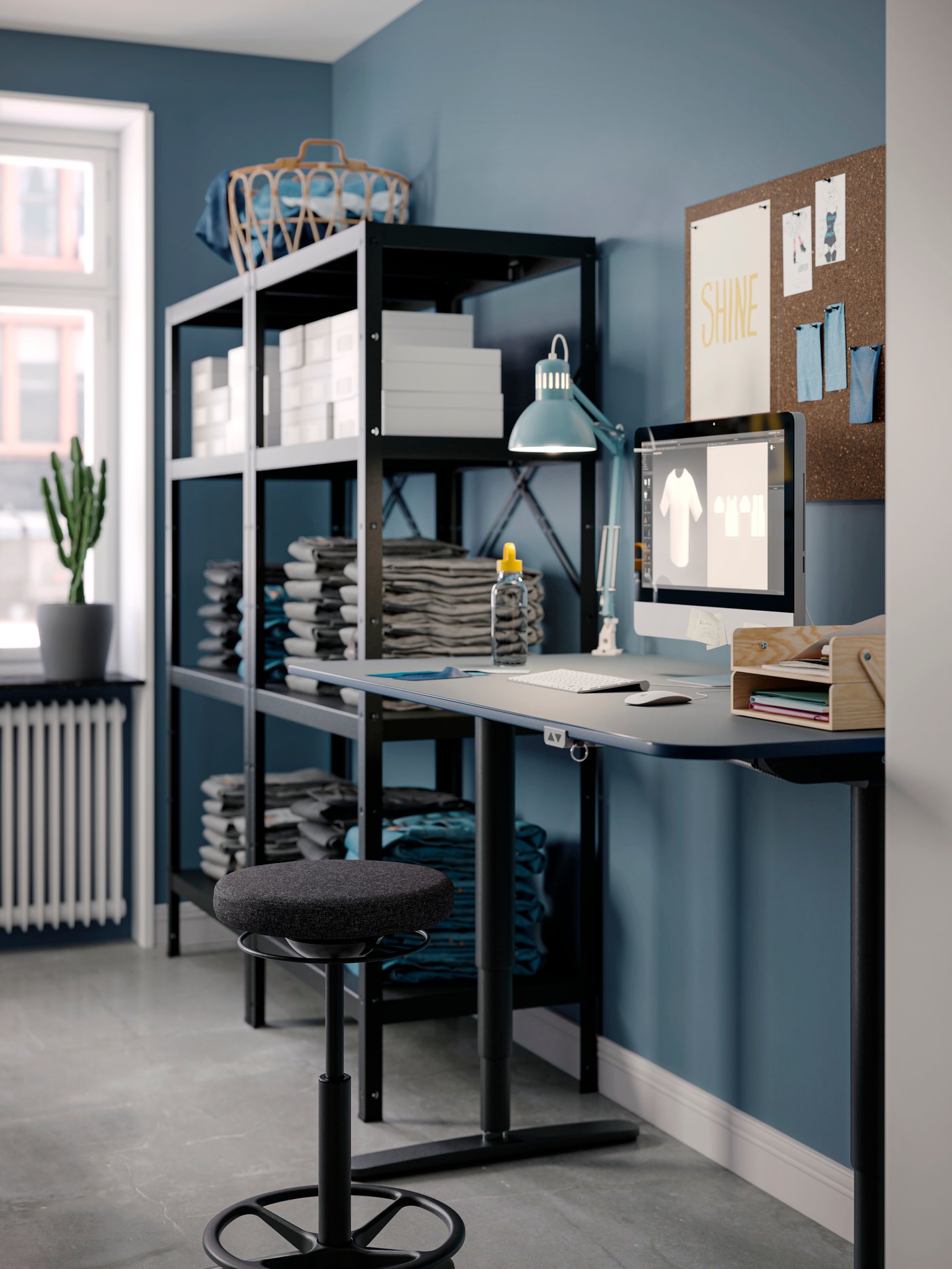 A room with blue walls with a BROR shelving unit next to a BEKANT sit-stand desk and a LIDKULLEN active sit-stand support.