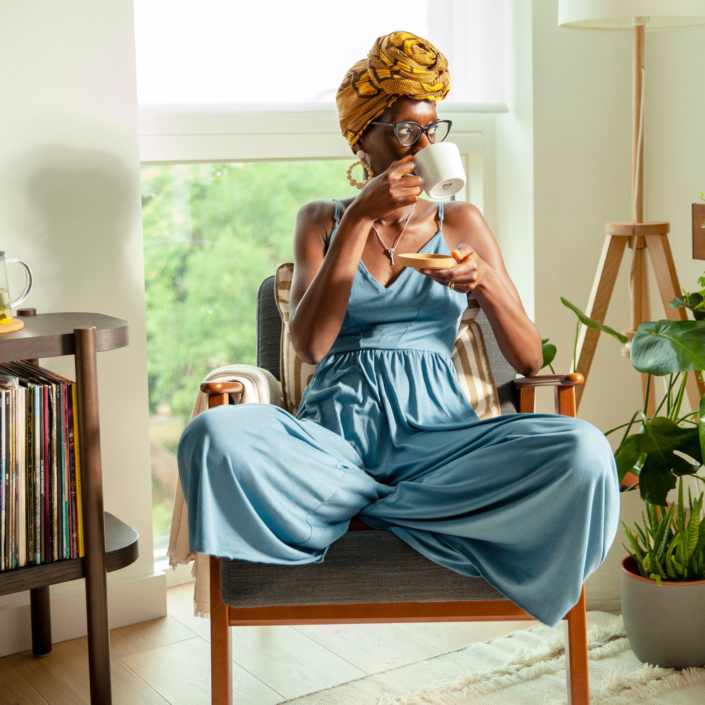 Una donna si rilassa in poltrona sorseggiando un tè da una tazza IKEA 365+.