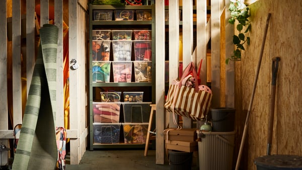 A long shot of a garage storage unit, filled with clear storage boxes revealing the contents inside. Various summer accessories have also been placed in the garage.