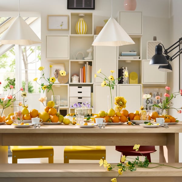 A BERGSHYTTAN table has a table setting with white plates and POKAL glasses and decorative oranges and lemons on plates.