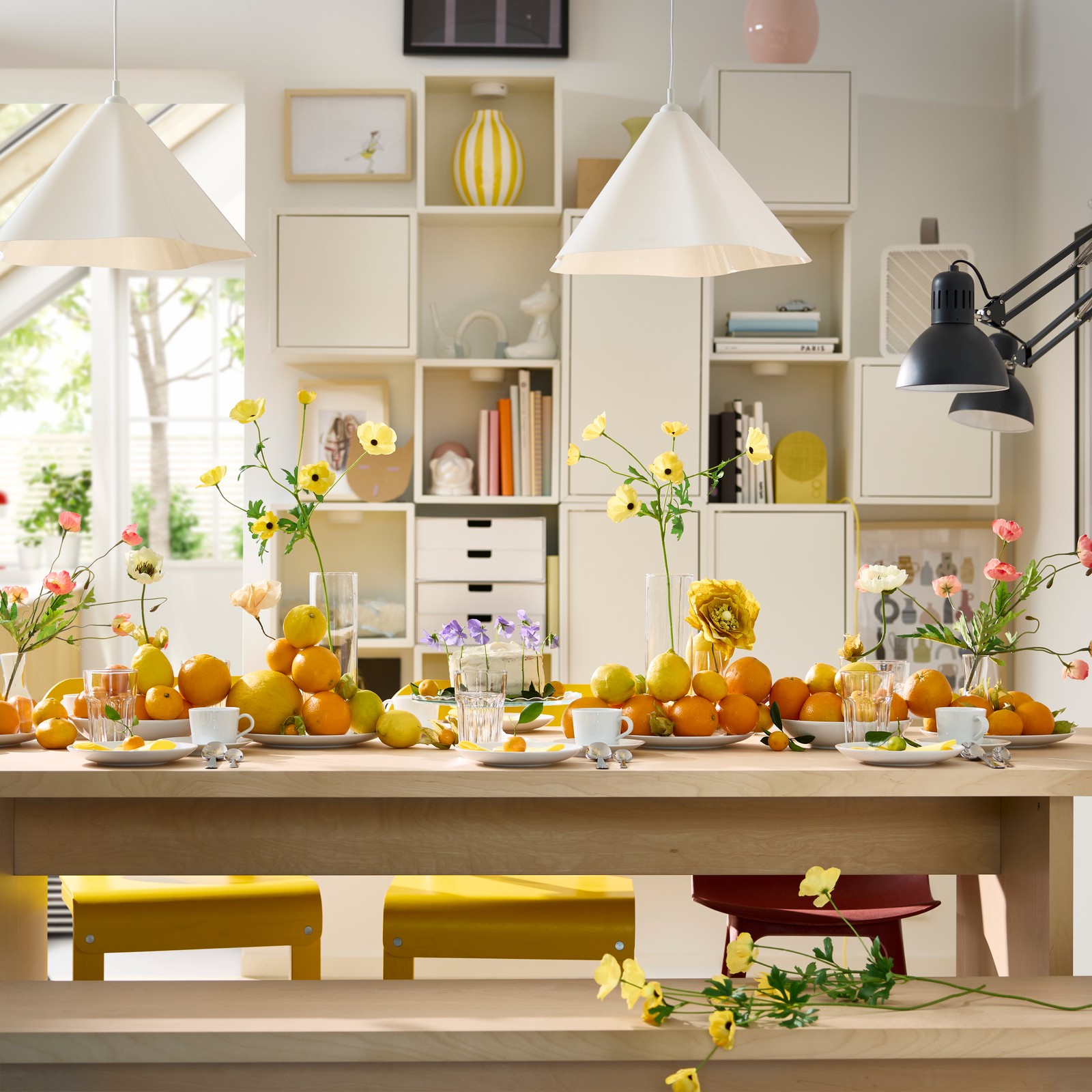 Unha mesa BERGSHYTTAN con pratos brancos, vasos POKAL e laranxas e limóns decorativos en pratos.