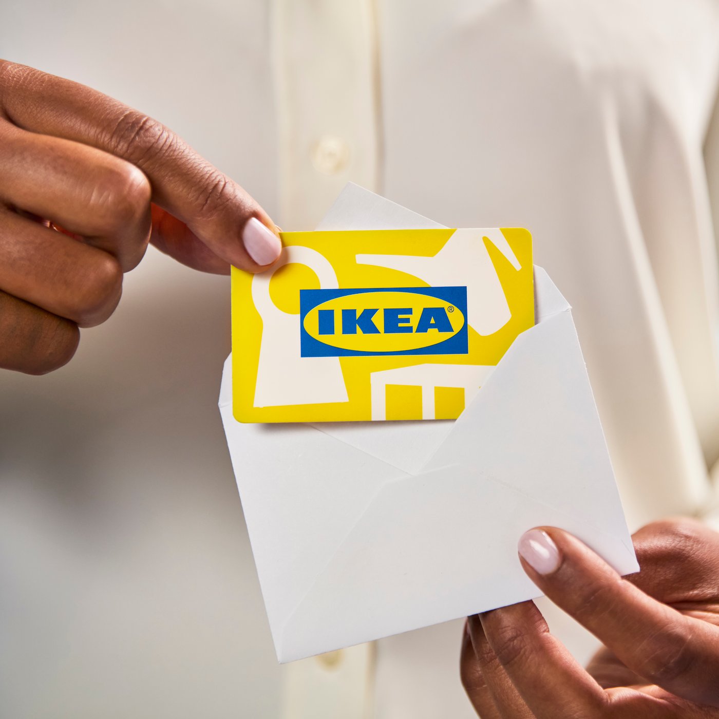 Una persona che mostra una busta contentente una Carta regalo IKEA.
