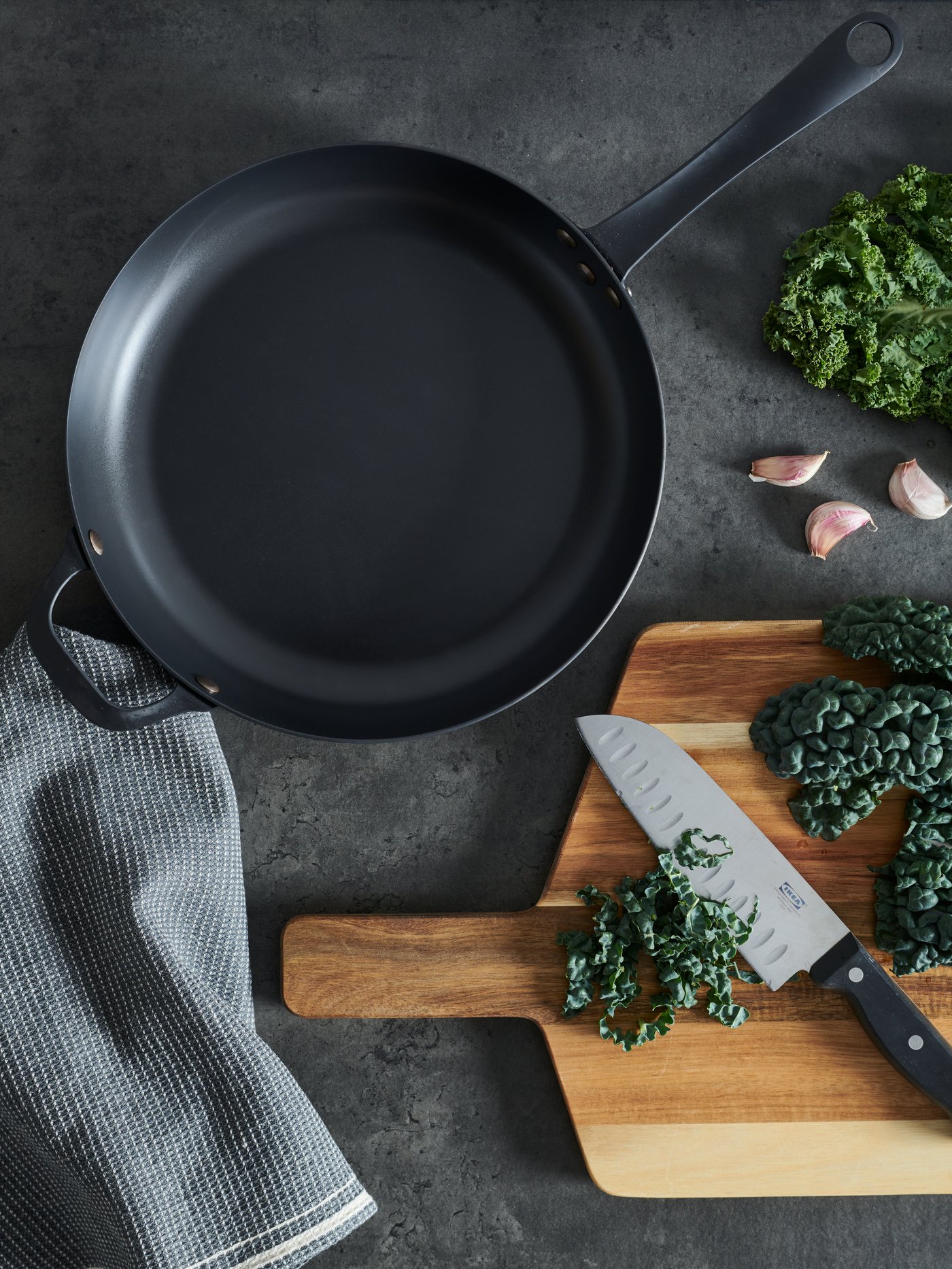 poêle sur un plan de travail gris et une planche à découper sur le côté