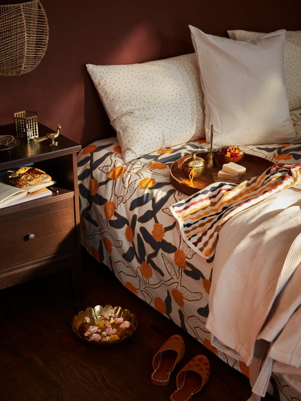 A colorful printed bed linen with white pillows.