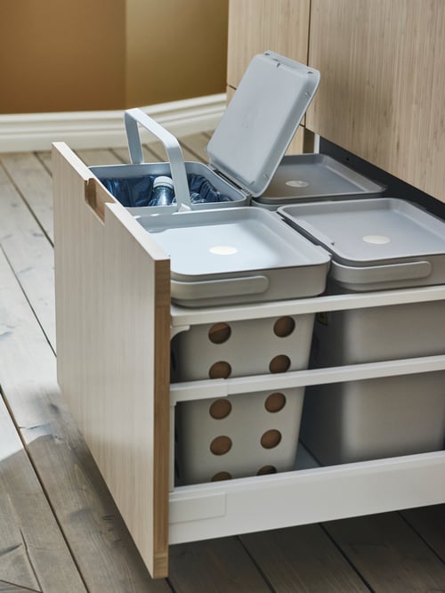 Kitchen close-up of a rectangular light grey waste sorting solution made out of polypropylene plastic, behind a drawer front.