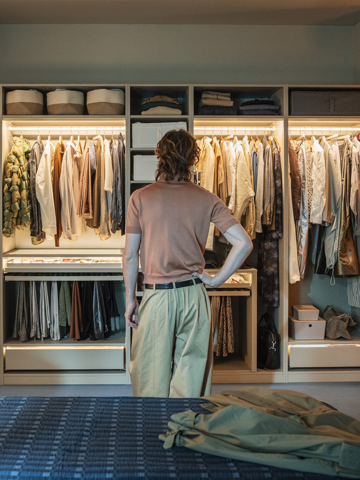 Un uomo sta osservando un armadio senza ante e diversi accessori SKUBB per organizzare i vestiti.
