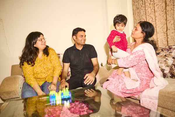 Portrait of two women, one man and one child sitting on a sofa smiling while having a conversation. 