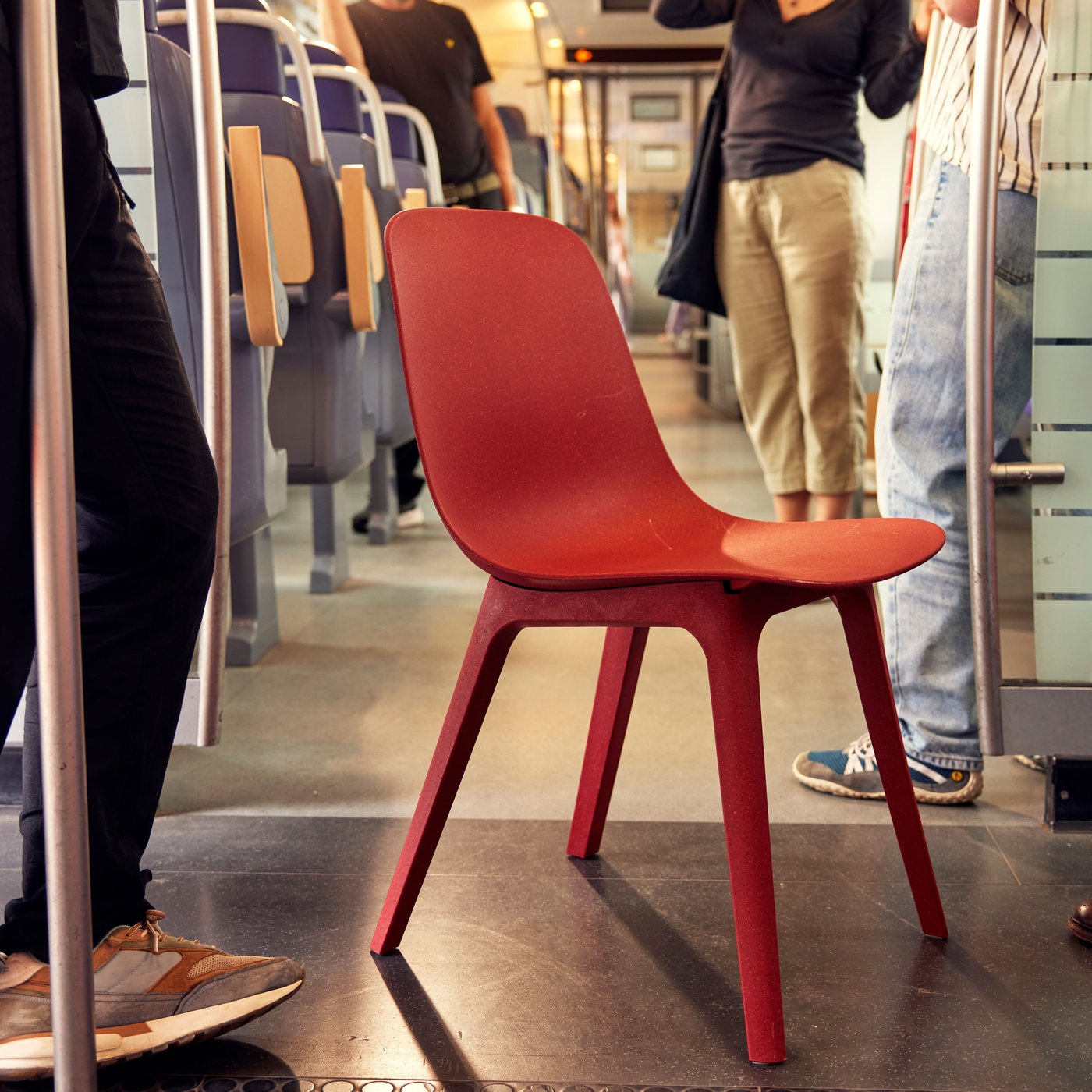 Punainen tuoli metrossa matkustajien välissä.