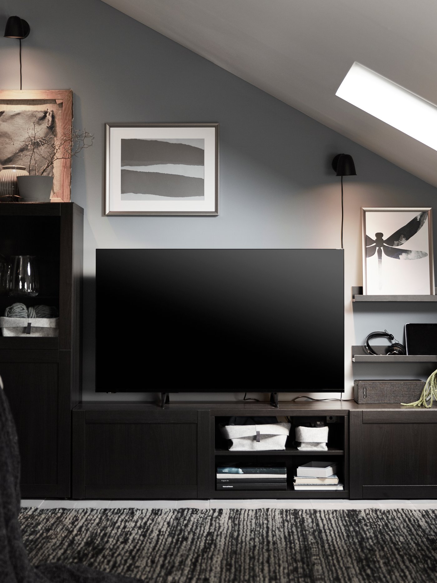 Un banc TV BESTA avec des portes HANVIKEN noires sur lequel est posé une TV.