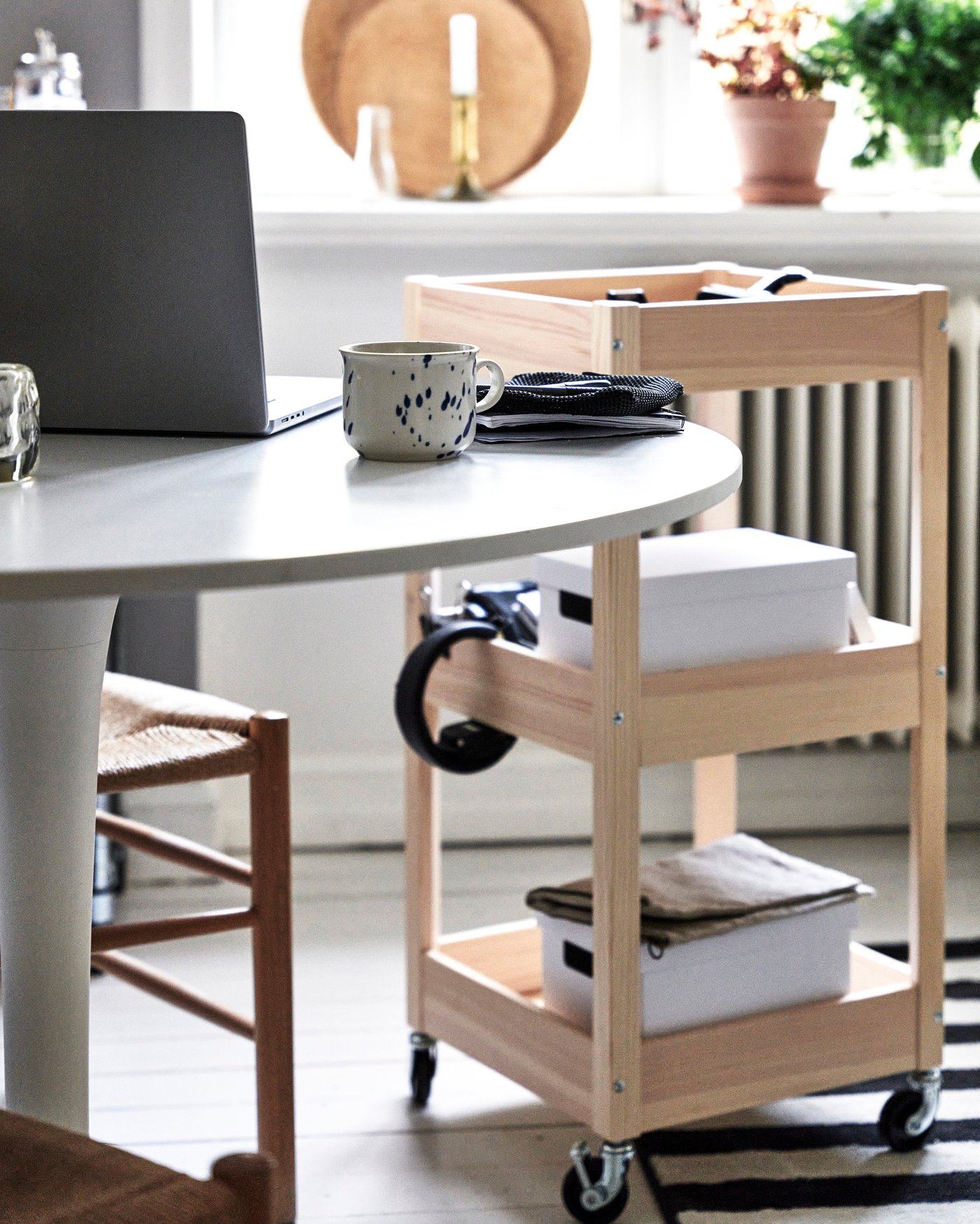 En rullvagn i trä står bredvid ett runt bord.