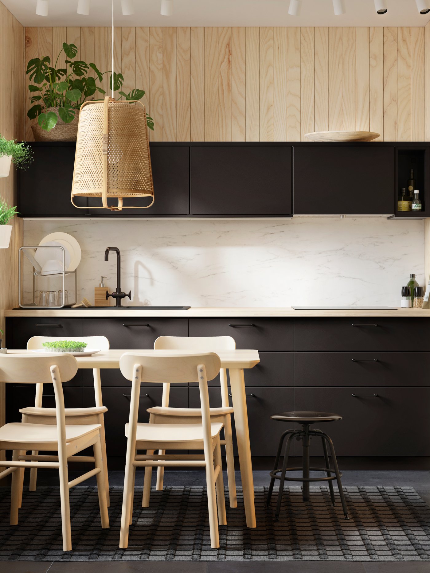 Cocina con una mesa, cuatro sillas, una lámpara de techo, un taburete, varios armarios bajos con cajones y un grifo de cocina.