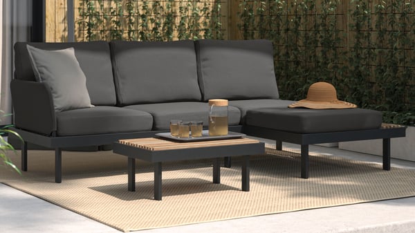 Een zwarte REVSKÄR tuinset staat op een beige MORUM laagpolig vloerkleed voor zowel binnen als buiten.