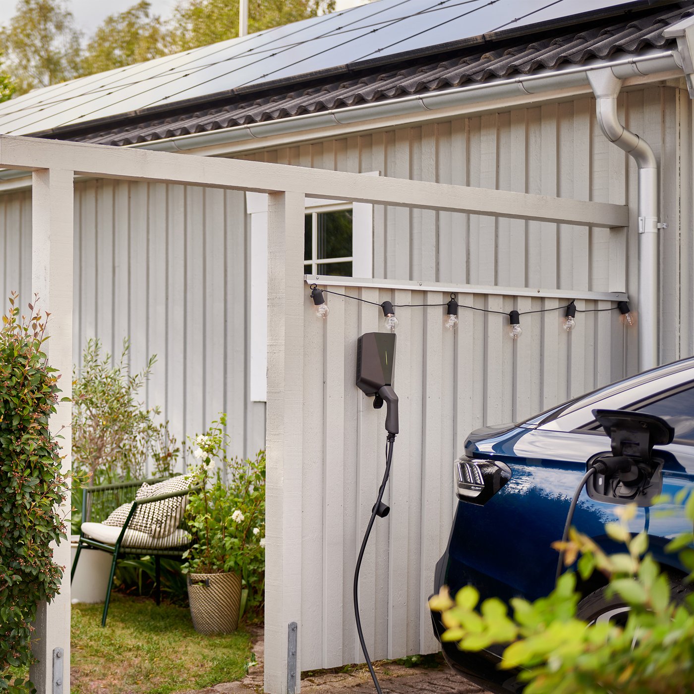 An electric car charging, plugged into a charger on the wall next to the parking space.