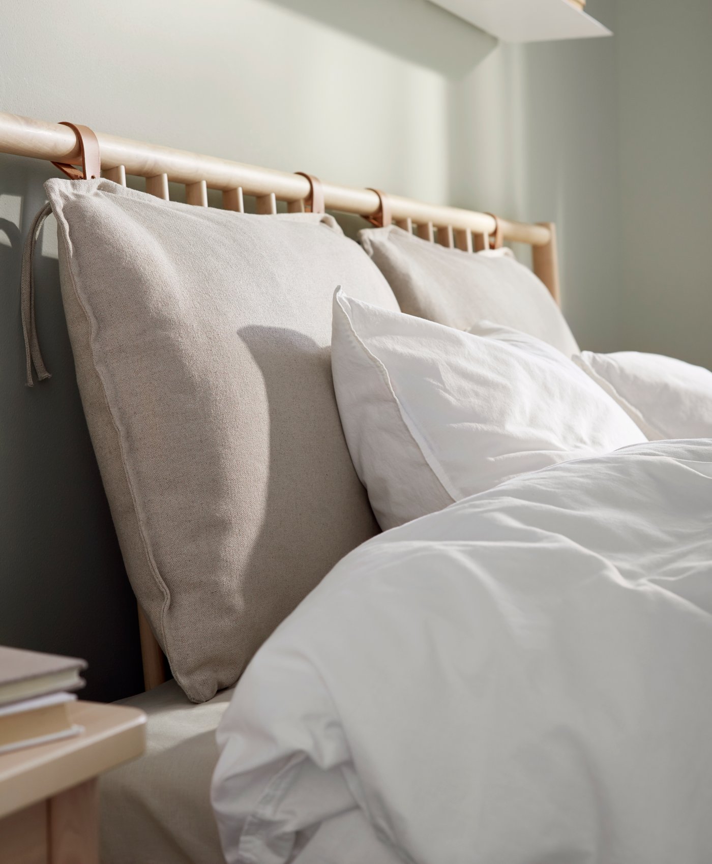 Tête de lit en bois clair avec coussins beiges et oreillers blanc