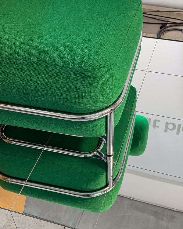 Dettaglio della nuova poltrona verde gonfiabile della collezione IKEA PS 26 con struttura tubolare metallica lucida in un ambiente interno.