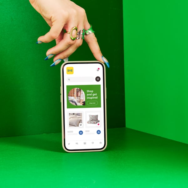 Dłoń trzymająca telefon z aplikacją IKEA w zielonej przestrezni.