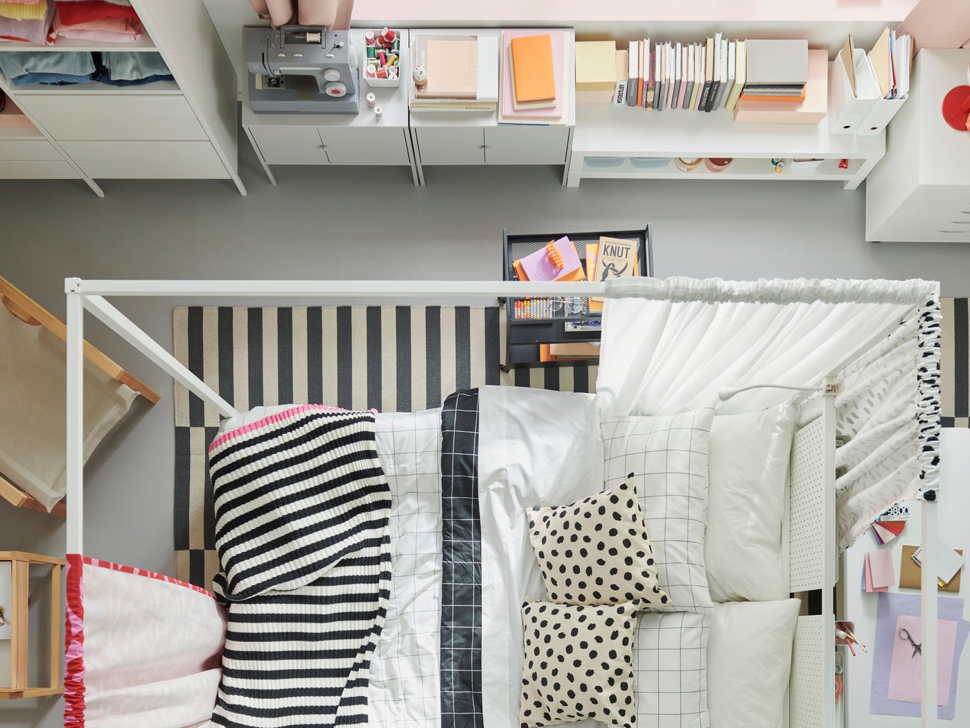 Vista superior de una recámara en tonos blancos con una cama con dosel VITARNA blanca en el centro, vestida con ropa de cama SLÅNHÖSTMAL.