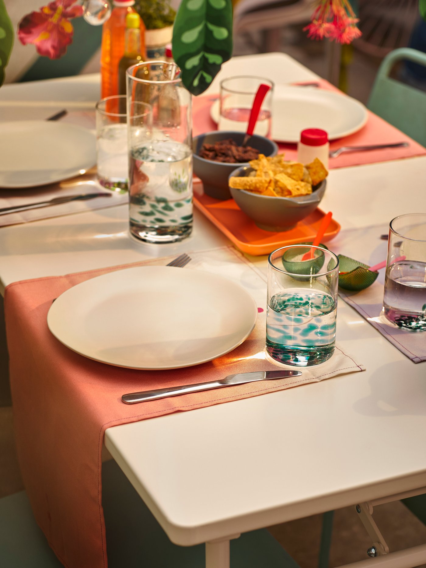 Una persona decora una ventana con una guirnalda ÖMSESIDIG de papel multicolor en forma de lindas hojas decorativas.